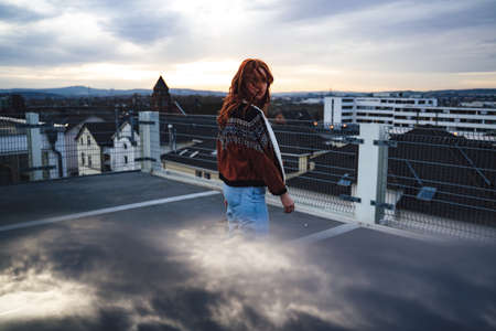 Side view of attractive woman with long red hairs looking to camera. Face is covered with strands of hairs. Outdoor photo, overcast weather.の写真素材