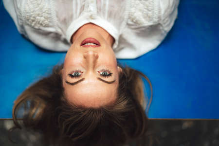 young woman laying on blue looking up day dreamingの写真素材