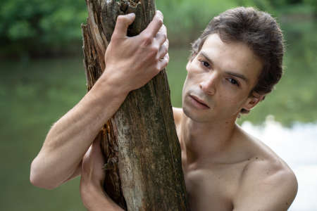 Close-up portrait of shirtless man holding wood in forestの写真素材