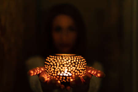 woman holds tealight candlelight in the darkの写真素材