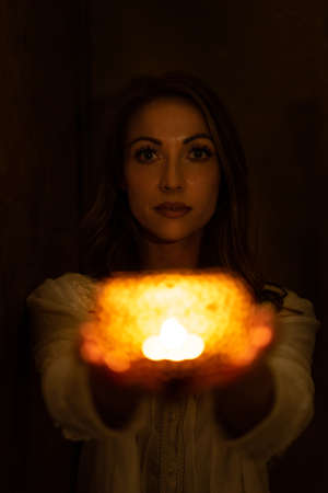 woman holds tealight candlelight in the darkの写真素材