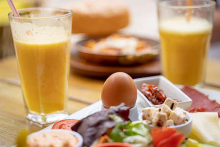 Close-up of egg with meal served by juice on table at sidewalk cafeの写真素材