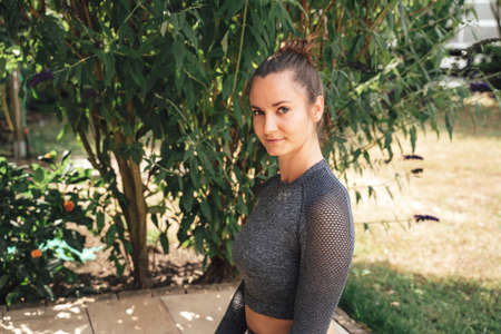 Portrait of confident young woman in sports clothing practicing yoga pose at patioの写真素材
