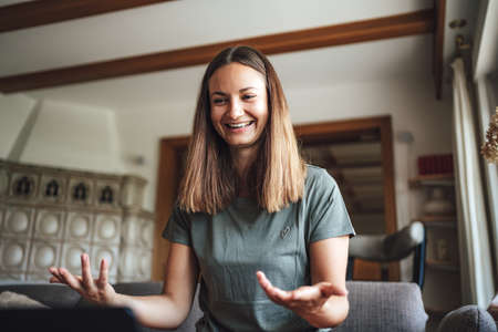 Smiling Caucasian woman gesturing while having conference video call at homeの写真素材