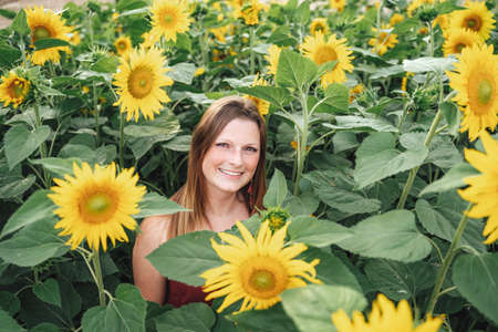 Portrait of carefree young woman smiling amidst sunflower plants at farmの写真素材