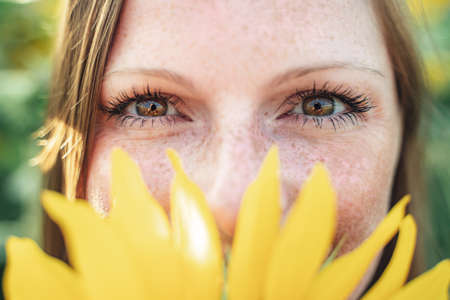 Close up portrait of Caucasian young woman hiding her face with yellow sunflowerの写真素材