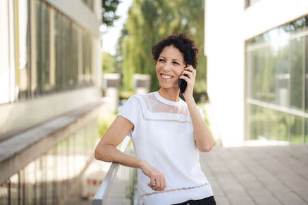 Confident mature businesswoman talking on mobile phone outside office buildingの写真素材