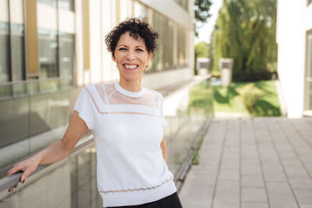 Portrait of smiling mature woman wearing t-shirt while standing outside office in cityの写真素材