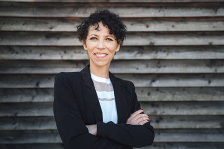 Portrait of smiling female entrepreneur standing arms crossed against shutter wallの写真素材