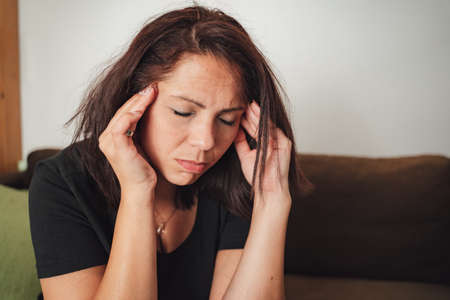 Close up of mid adult Caucasian woman suffering from headache at homeの写真素材