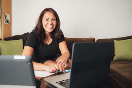 Smiling mid adult businesswoman using laptop while working from home during lockdownの写真素材
