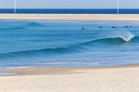 A group of lone surfers sitting in the ocean in front of Baleal islandの写真素材