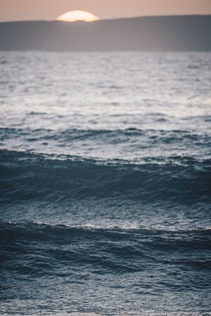 Waves at sunset with blurry sunsetの写真素材