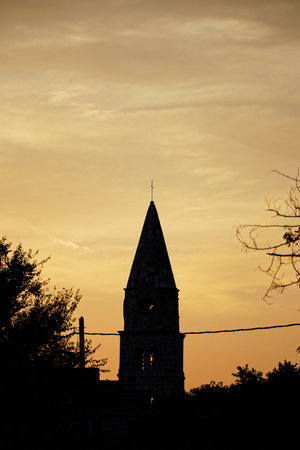 View of an silhouette church tower against a sunset skyの写真素材
