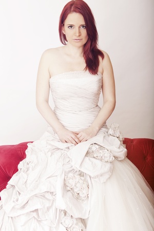 young red haired beautiful bride on red sofa の写真素材