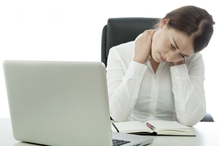 young brunette business woman pain neck behind computerの写真素材