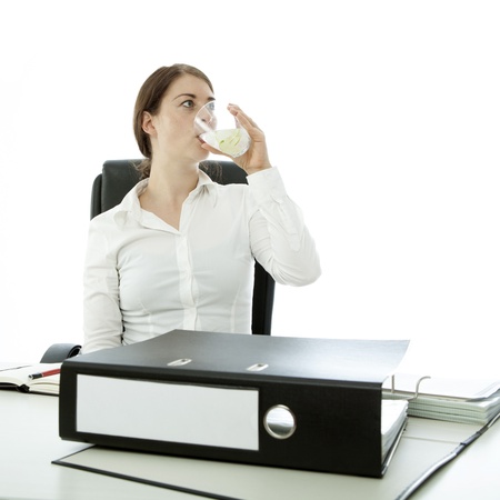 young brunette woman drinking water in front of documentsの写真素材