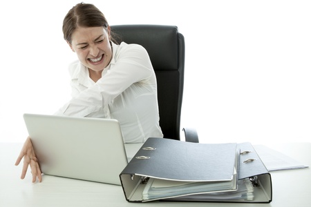 young brunette business woman in rage and throw laptop deskの写真素材