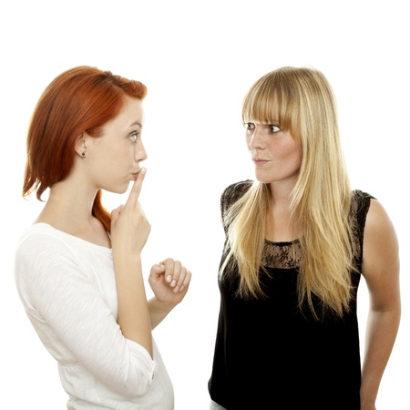 young beautiful red and blond haired girls sign it is a secret in front of white backgroundの写真素材
