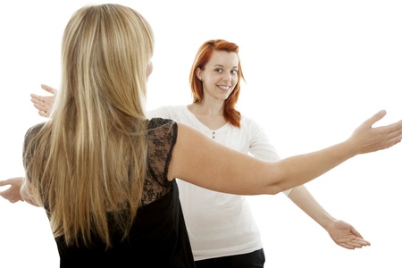 young beautiful red and blond haired girls want to give a hug in front of white backgroundの写真素材