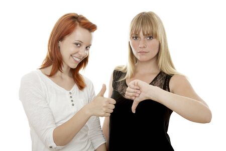 young beautiful red and blond haired girls thumb up and down in front of white backgroundの写真素材