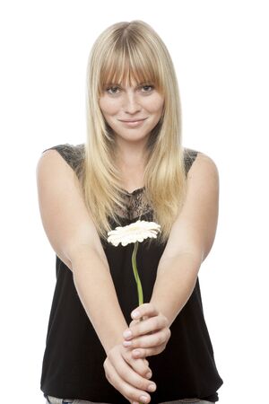 young beautiful blond haired girl gives you a flower in front of white backgroundの写真素材
