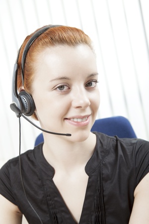 Head and shoulders portrait of an attractive smart young woman receptionist, call centre operator or public relations support wearing a headset and microphoneの写真素材