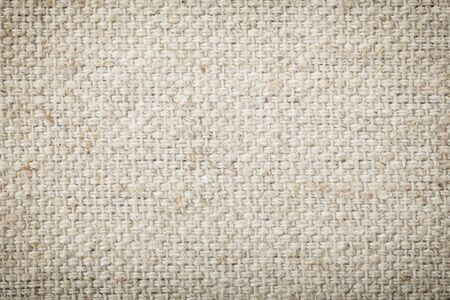 Background texture of natural unbleached woven canvas or burlap showing fiber and weave texture and pattern with light corner vignettingの写真素材