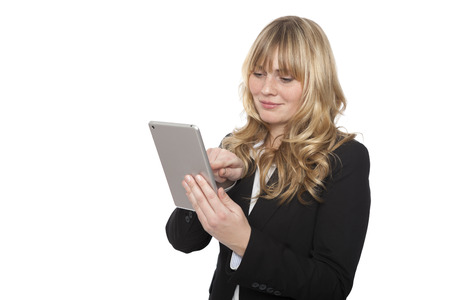 Businesswoman standing surfing the internet on her tablet computer using her fingers on the touchscreen, isolated on whiteの写真素材
