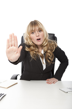 Young businesswoman saying - No - holding up her hand in a stop gesture as she calls a halt to proceedings or tells someone to go away, on whiteの写真素材