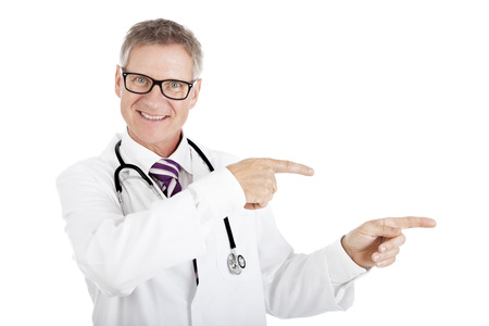 Friendly smiling doctor pointing to the right of the frame, with both hands drawing attention to blank white copyspace.の写真素材