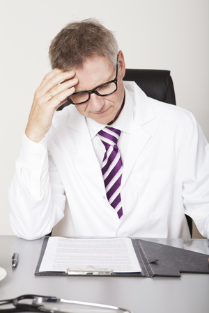 Male Health Professional Seriously Reading Reports on Tableの写真素材