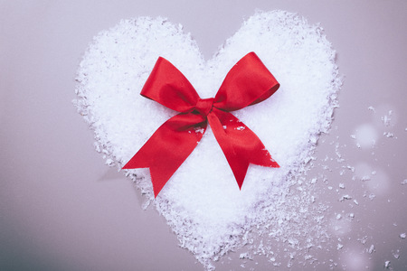 snow heart with red ribbon loopの写真素材