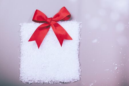 christmas gift box in snow with red ribbonの写真素材