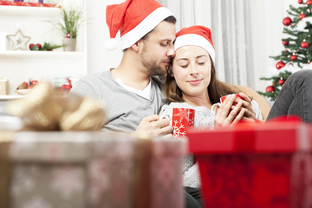 young christmas couple relaxing and enjoying hot tee on sofa after christmas troubleの写真素材