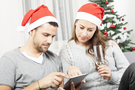 happy young couple use tablet pc for christmas on sofaの写真素材