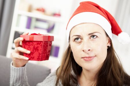 happy young girl want to guess christmas gift and looks a bit confusedの写真素材
