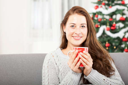 young good looking girl is relaxing with warm tea at christmas eveの写真素材