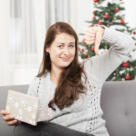 young girl is unhappy about christmas gift and thumbs downの写真素材