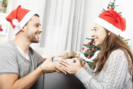 young man give her girlfriend a present box for christmas eveの写真素材