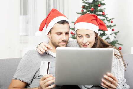 happy couple shopping online present gifts on sofa indoors using credit cardの写真素材
