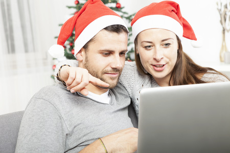 happy couple buying online presents on sofa indoors using credit cardの写真素材