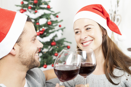 happy young couple drinking wine on sofa at christmas eveの写真素材