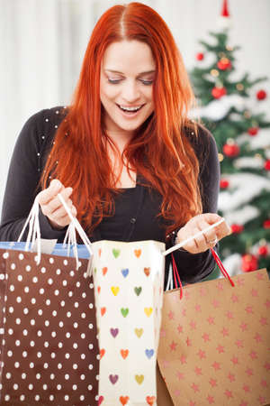 young happy red haired girl with a lot of christmas bags is love shopping present gift boxesの写真素材