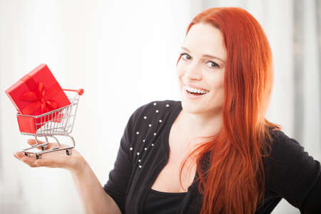 young happy christmas girl showing mini shopping trolly cart, for presents or giftsの写真素材