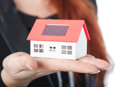 young beautiful business woman with close up of mini solar house,isolated on white backgroundの写真素材