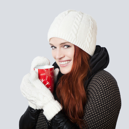young wonderful girl with scarf and gloves and hot mug of tea, isolated on grey backgroundの写真素材