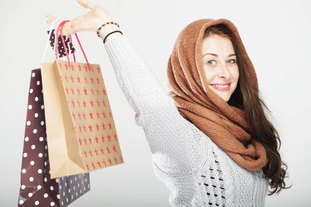 young happy playful cute winter girl with shopping bags, isolated on grey backgroundの写真素材