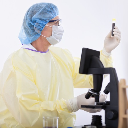 portrait of scientist or doctor in protective gear holding blood sampleの写真素材