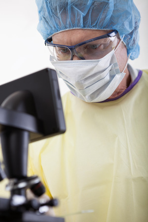 portrait of scientist or doctor in protective gear working with microscope and blood, in lab or hospitalの写真素材